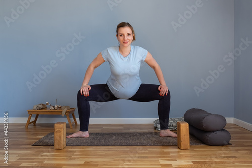 Pregnant woman standing in Sumo Squat exercise, Goddess pose photo