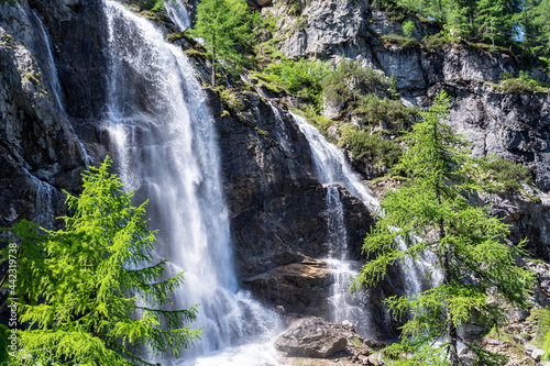 Close up of a waterfall in the Austrian Alps on a sunny summer day with rocks and trees