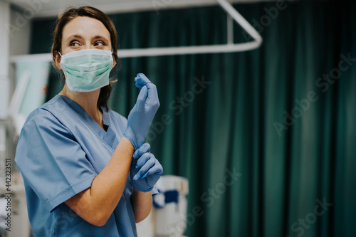 Female nurse with a mask putting on gloves photo