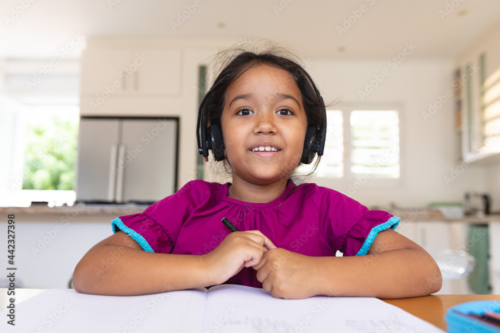 Happy hispanic girl wearing headphones smiling during online school lesson Happy hispanic girl wearing headphones smiling during online school lesson