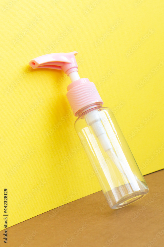 Mock up cosmetic jar for cream, shampoo, serum on bright yellow paper background with shadows. Empty plastic portable cream jar and white flowers. Close up