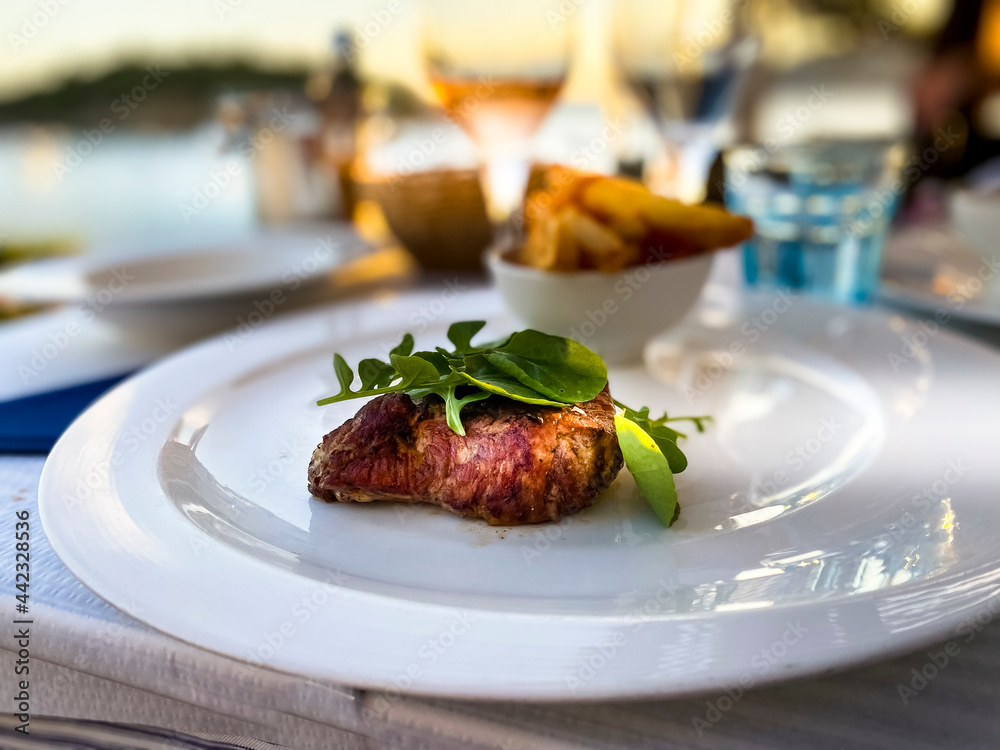 Spain, Mallorca, Port de Andratx, ghriled fillet steak in the evening sun by the sea Spain, Mallorca, Port de Andratx, ghriled fillet steak in the evening sun by the sea
