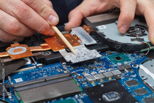 An office equipment repairman cleans bad thermal paste from the laptop's cooling system
