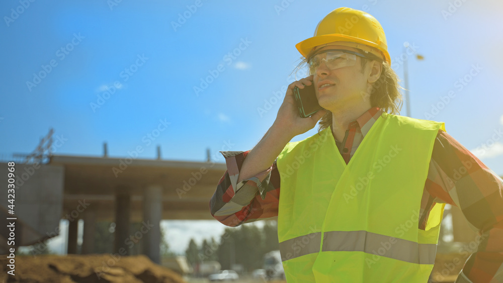 Builder talking by smartphone at construction site. Builder talking by smartphone at construction site.