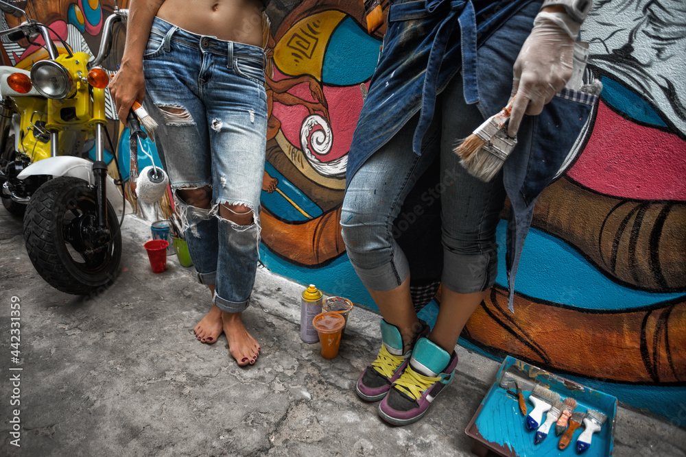 Obraz premium Street art. Cheerful young women painting on the wall. Street art.