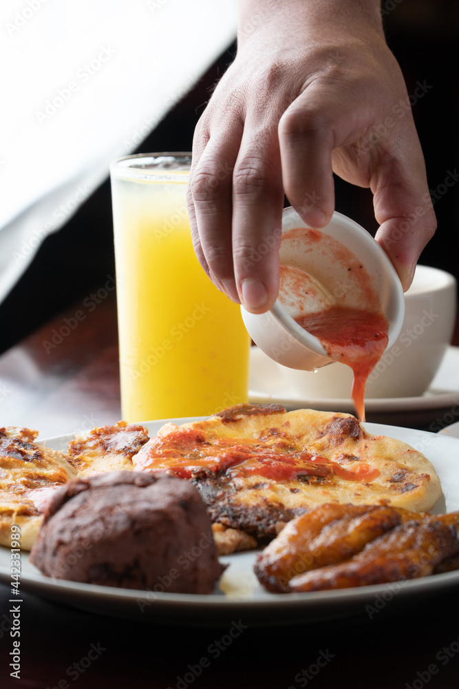 adding tomato sauce to a couple of pupusas Stock Photo Adobe Stock