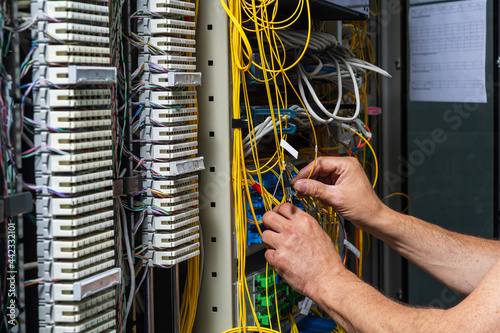 Hands of a technician crossing a telecommunication panel cable in a rack