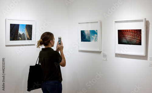 Woman in an art exhibition taking a photo of an art