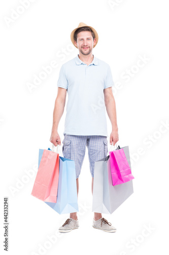 Vertical full length studio portrait of handsome man wearing summer outfit carrying shopping bags, white background
