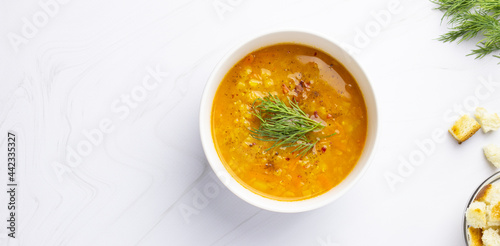 Red lentil soup with ingredients on a light background. Traditional Turkish or Arabic spicy lentil and vegetable soup, healthy vegan food. Top view, copyspace.