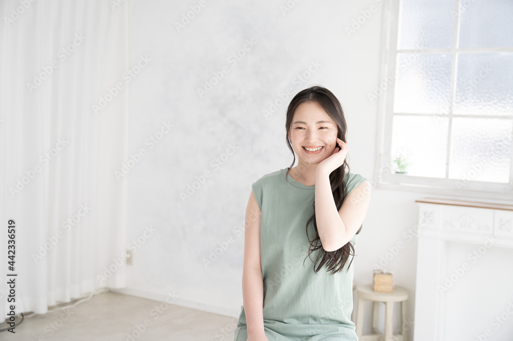 お肌の調子を気にして微笑む若い日本人女性　左にコピースペースあり