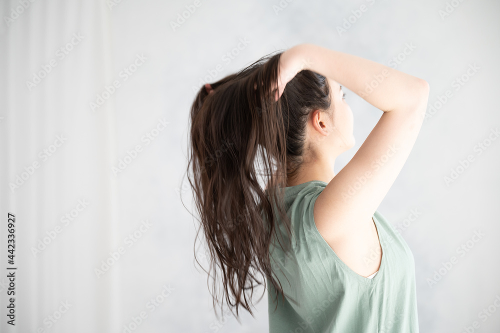 Fototapeta premium ヘアケアなどに使えそうな髪の毛をかきあげる後ろ姿の美しい女性2 左あきコピースペース