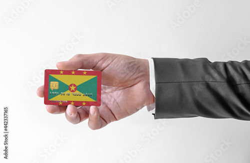 Bank credit plastic card with flag of Grenada holding man in elegant suit
