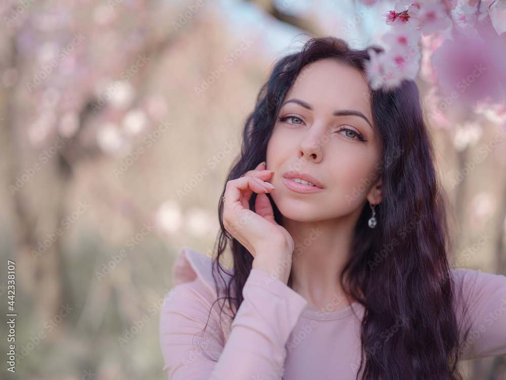 A beautiful young woman near a blooming spring pink tree A beautiful young woman near a blooming spring pink tree
