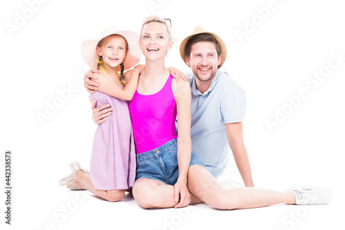 Horizontal studio portrait of family with cute daughter wearing summer outfits sitting on floor, white background