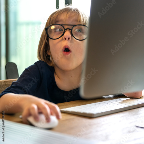 Young girl with glasses shocked from using a computer