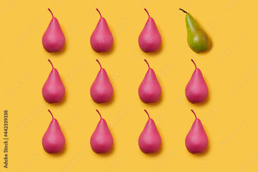 Pattern of pink painted pears on vibrant yellow background with one green pear. Differentiation and unique idea. Creative fruit food texture concept. Pattern of pink painted pears on vibrant yellow background with one green pear. Differentiation and unique idea. Creative fruit food texture concept.