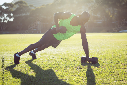 African amercian muscular man exercising outdoors with dumbbells photo