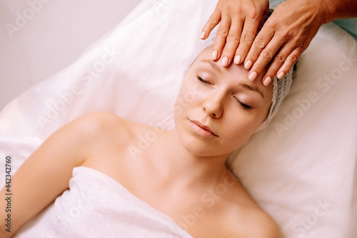 Close-up of young smiling young woman getting spa massage treatment at beauty spa salon. Spa skin and body care. Facial care. Cosmetology 