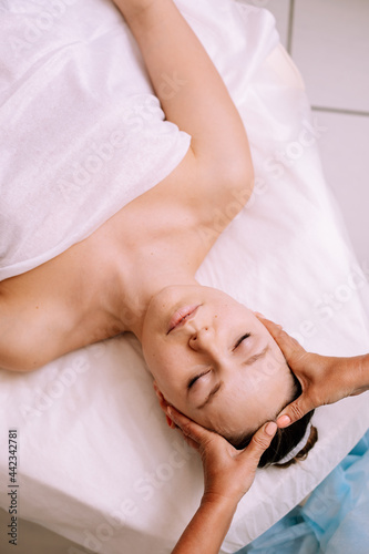 Close-up of young smiling young woman getting spa massage treatment at beauty spa salon. Spa skin and body care. Facial care. Cosmetology 