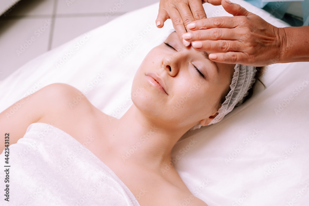 Close-up of young smiling young woman getting spa massage treatment at beauty spa salon. Spa skin and body care. Facial care. Cosmetology Close-up of young smiling young woman getting spa massage treatment at beauty spa salon. Spa skin and body care. Facial care. Cosmetology