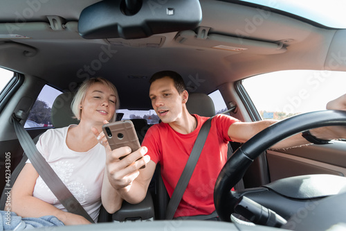 Young couple driving car and using digital map on smartphone © Komarov Dmitriy