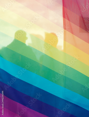 Silhouettes of two behind the rainbow flag