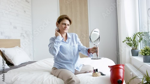 Disabled mature woman sitting on bed indoors at home, looking at camera. Morning routine with leg amputee concept. photo