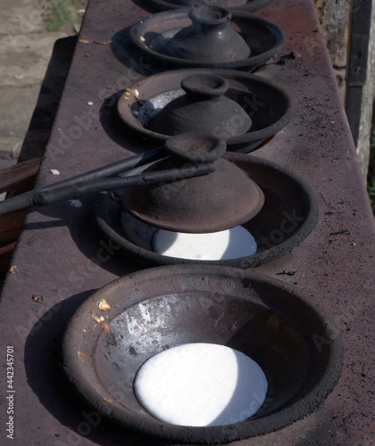 Close up of mother's hand cooking serabi or pancakes in a frying pan made from soil photo