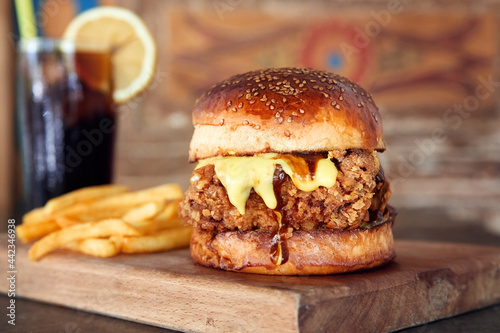 Delicious homemade crispy chicken burger on wooden tray with coke and fires.
