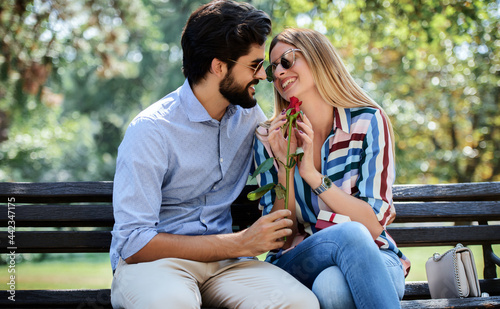 Meeting in the park. Young man surprised his girlfriend with a red rose. Love, dating, romance