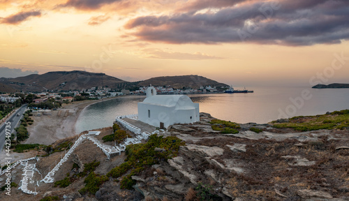 Greece, Kea Tzia island. Small white church on a rocky hill, over Korissia port at sunset photo