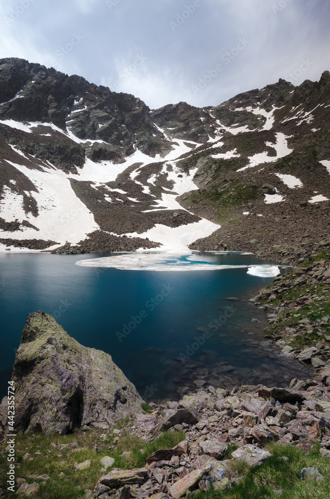 Obraz premium Mountain lake of Laroussa, in Stura Valley, Piedmont, between maritime alps park (italy) and mercantour park (france). The blue water is surrounded by peaks and last snow even in summer