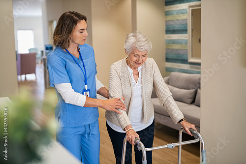 Obraz na plátne Nurse helping senior woman to walk at private clinic