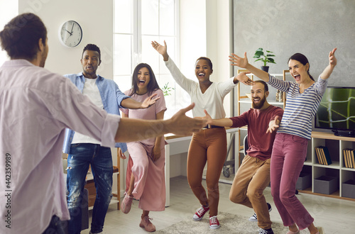 Congratulations: Diverse group of excited young people meet man who's achieved great success. Long time no see: Happy, emotional friends spread arms wide open to hug friend who's finally back home