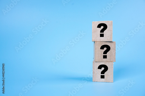 Question mark symbol on a stack of wooden cube over blue background