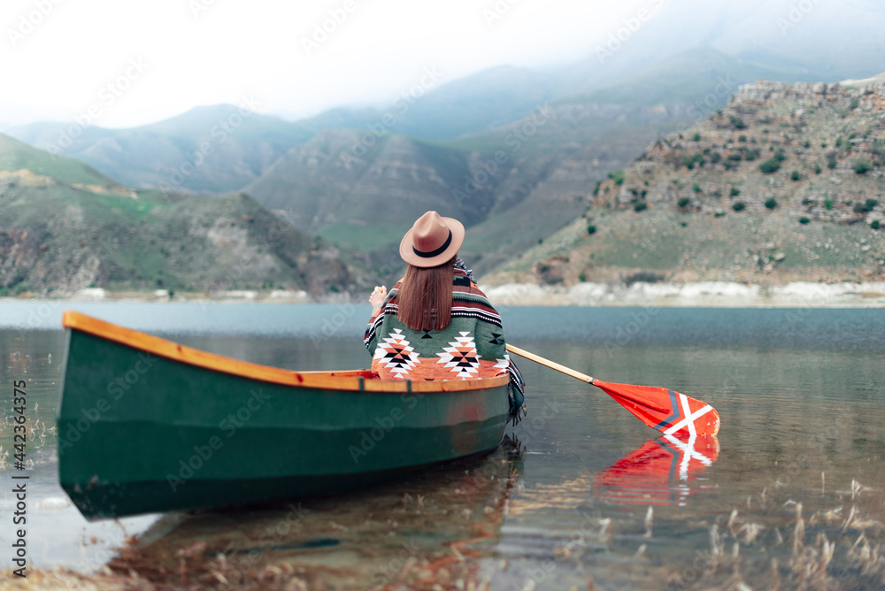 Girl canoeing on a lake in the mountains on a cloudy day. Moody atmosphere on Lake Gizhgit in the village of Bylym, Kabardino-Balkaria