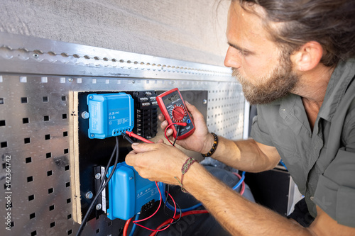 Man testing electronic components with a multimeter photo