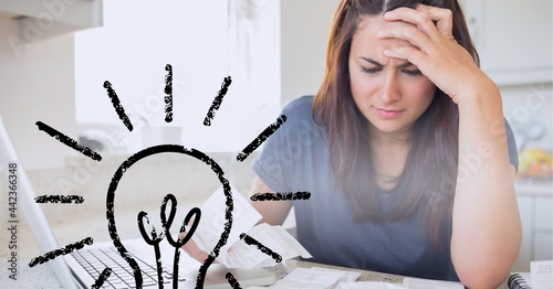 Glowing light bulb icon against stressed caucasian woman calculating finance at home