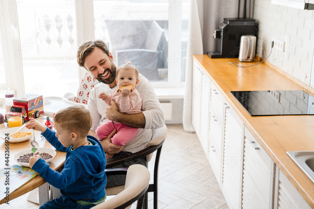 Fototapeta premium White father smiling while having breakfast with his children at home