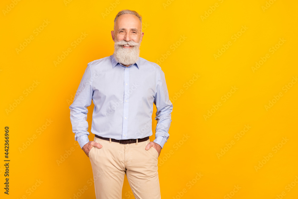 Photo of cheerful beard elder man stand wear blue shirt pants isolated on yellow color background Photo of cheerful beard elder man stand wear blue shirt pants isolated on yellow color background