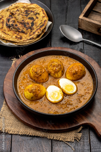 Fried egg curry or Anda Masala served in a bowl with lachha parantha
