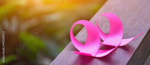 Pink ribbons on wooden table, sunlight and blurred background, concept for breast cancer awareness around the world. Soft and selective focus on pink ribbons.