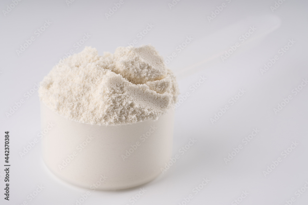 Heap of protein powder on white background. Scoops Of Protein Powder. Measuring spoon and heap of vanilla protein powder.