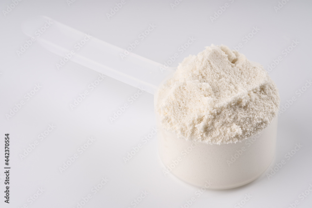 Heap of protein powder on white background. Scoops Of Protein Powder. Measuring spoon and heap of vanilla protein powder. Heap of protein powder on white background. Scoops Of Protein Powder. Measuring spoon and heap of vanilla protein powder.