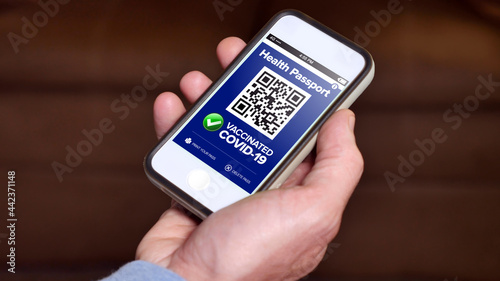 A smartphone showing a virtual COVID-19 digital vaccination card. Showing vaccination proof was a controversial topic after the Coronavirus pandemic of 2020. Fictional phone and interface.	
