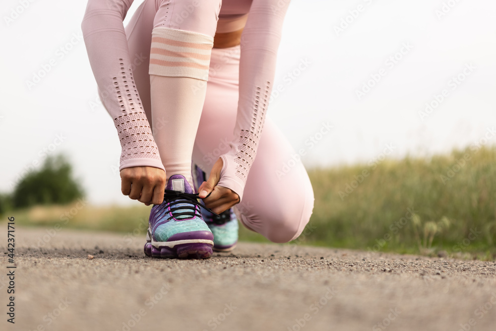 Young female runner, athlete is jogging at road in summer sunshine. Beautiful caucasian woman training, listening to music. Concept of sport, healthy lifestyle, movement, activity.
