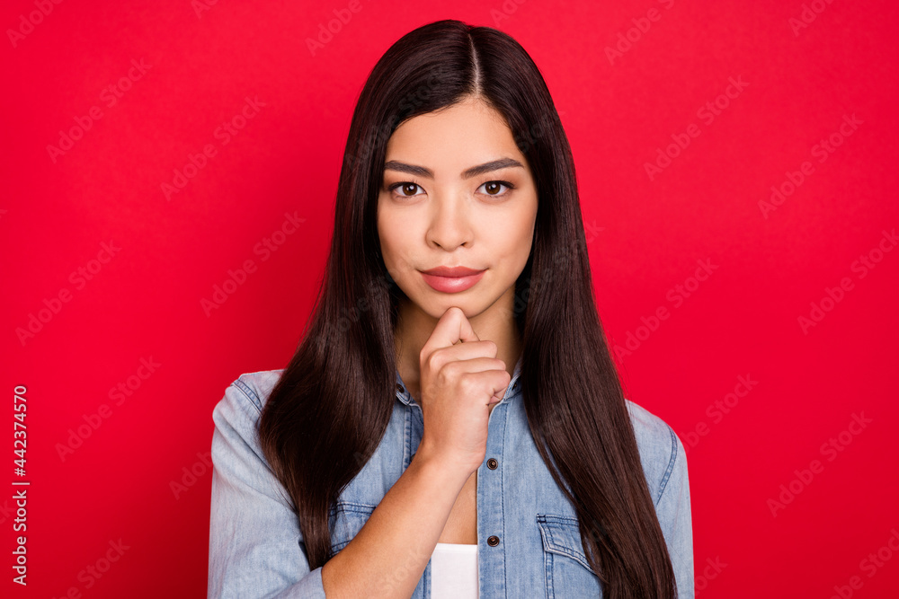 Photo of young attractive asian girl serious hand touch chin think ponder brainstorming isolated over red color background Photo of young attractive asian girl serious hand touch chin think ponder brainstorming isolated over red color background