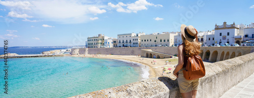 Traveling in Italy. Panoramic view of female backpacker with hat in Gallipoli village, Salento, Italy. photo