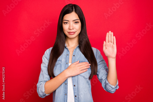 Portrait of attractive calm girl praying showing palm giving promise isolated over bright red color background